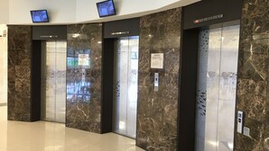 Un área de ascensor moderna con paredes de mármol, pantallas digitales y un suelo de baldosas impecable.