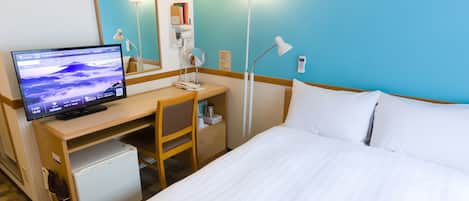 Habitación de hotel con cama, escritorio con computadora, silla, lámpara de escritorio, reloj y espejo montado en la pared.