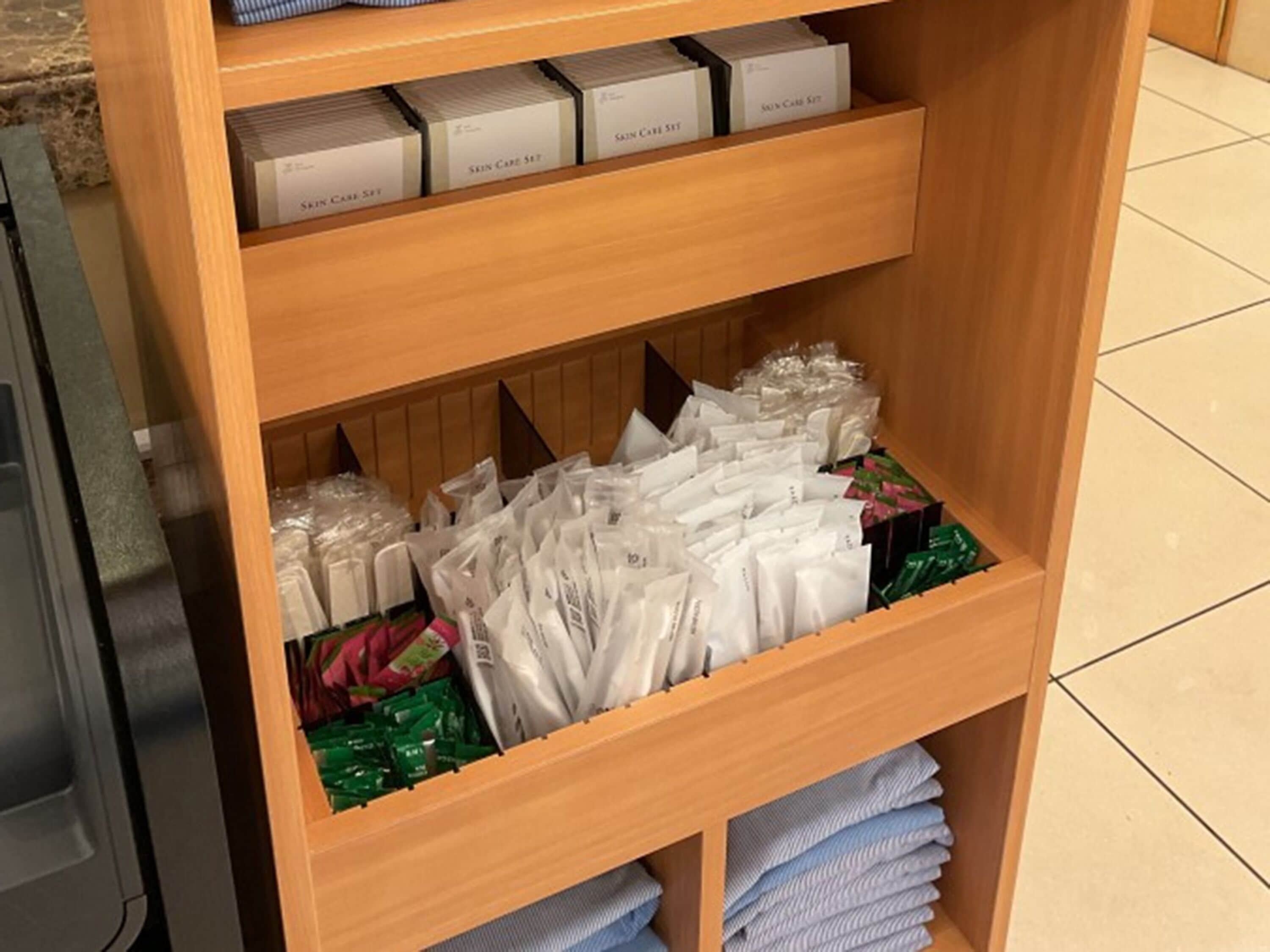 A wooden shelf with boxes labeled 'SUN CARE SET' and a drawer below filled with various items.
