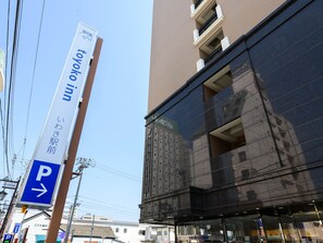 Ein hohes Gebäude mit einem Schild für 'Toyoko Inn' und einem Parkplatzschild.