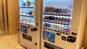 Deux distributeurs automatiques, portant l’inscription « SMILE BOX », proposent une variété de boissons et d’en-cas.