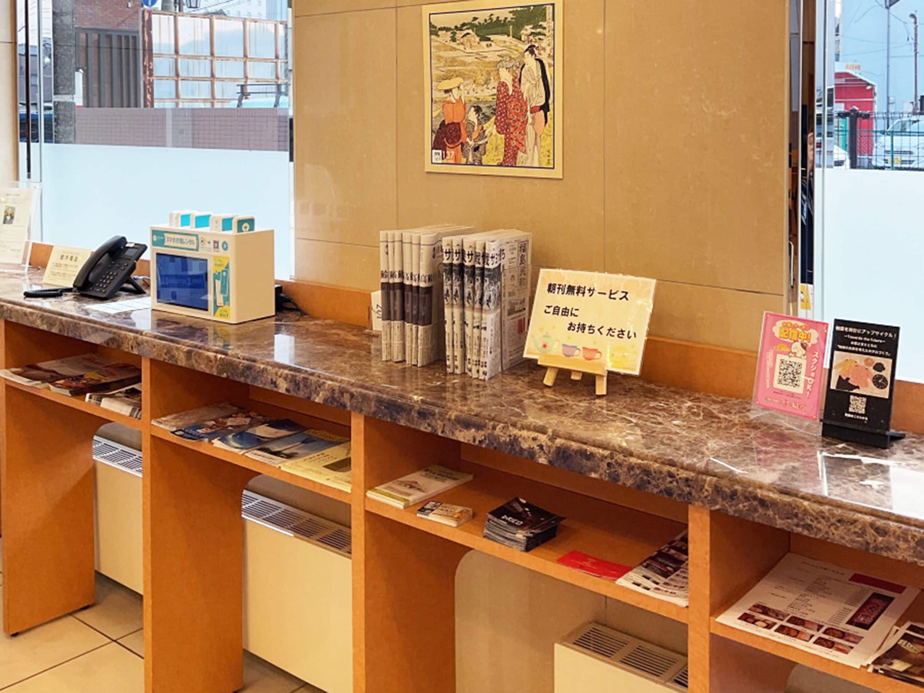 Una recepción con un teléfono, un pequeño atril con revistas y un letrero con texto en japonés.