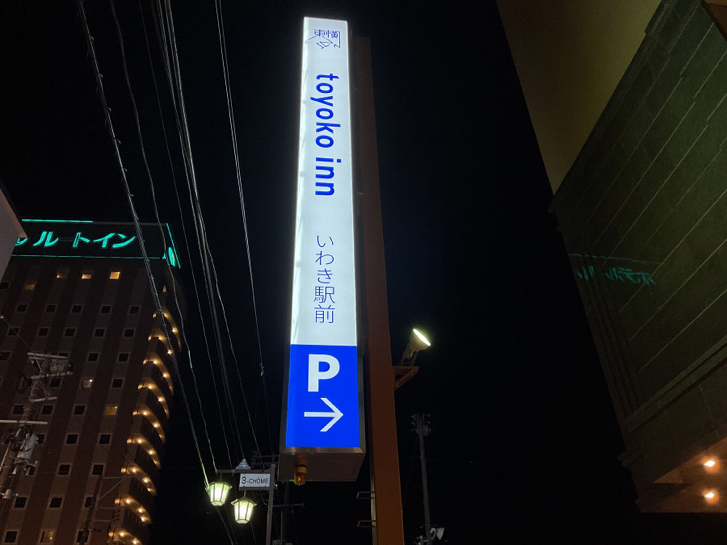 Señal vertical de 'Toyoko Inn' con una flecha direccional apuntando a la derecha, que indica la ubicación del estacionamiento.