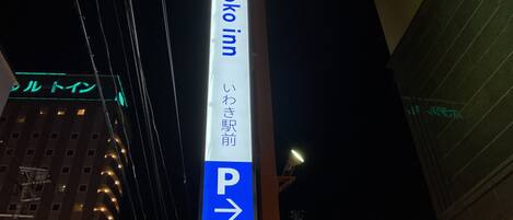 Señal vertical de 'Toyoko Inn' con una flecha direccional apuntando a la derecha, que indica la ubicación del estacionamiento.