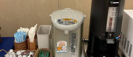 A kitchen with a coffee maker, a rice cooker, and containers of utensils.