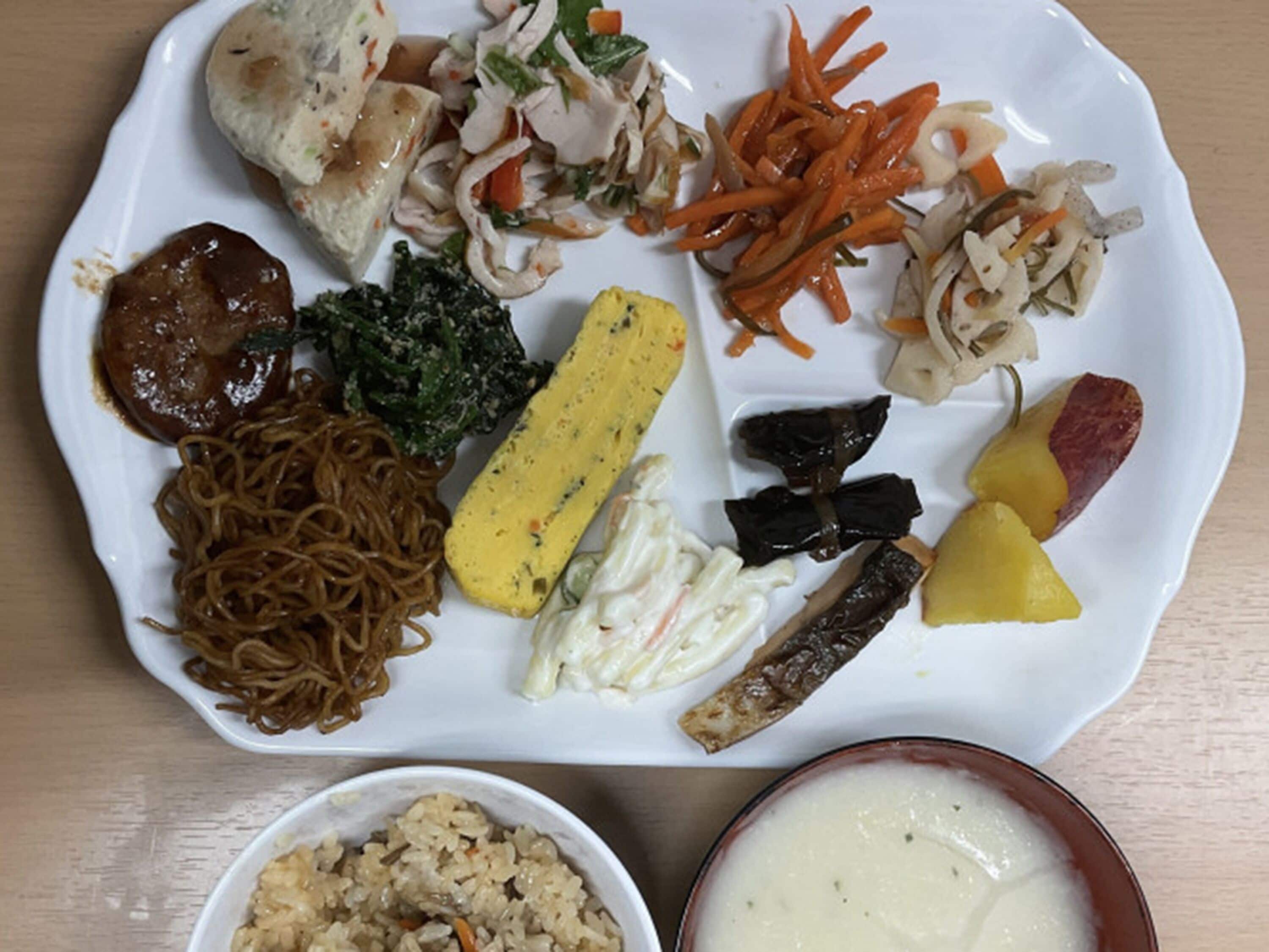 Un plato con diversos platillos, incluyendo fideos, verduras y un tazón de sopa.