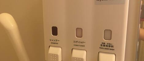 A wall-mounted control panel with buttons labeled for shampoo, conditioner, and body wash.