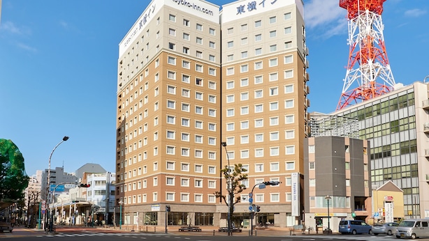 A hotel with a modern design, featuring a prominent tower in the background. - Toyoko Inn Shonan Hiratsuka Station Kita 1 (Hiratsuka)