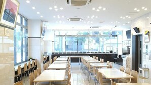 A spacious dining area with multiple tables and chairs, large windows providing natural light, and a modern interior design. - Toyoko Inn Shonan Hiratsuka Station Kita 1 (Hiratsuka)