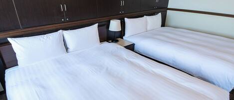 A hotel room with two beds, a nightstand, and a wardrobe.