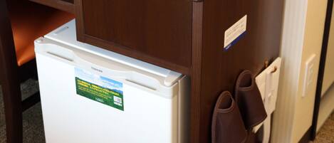 A refrigerator with a Toshiba sticker, a pair of brown slippers, and a white door handle.