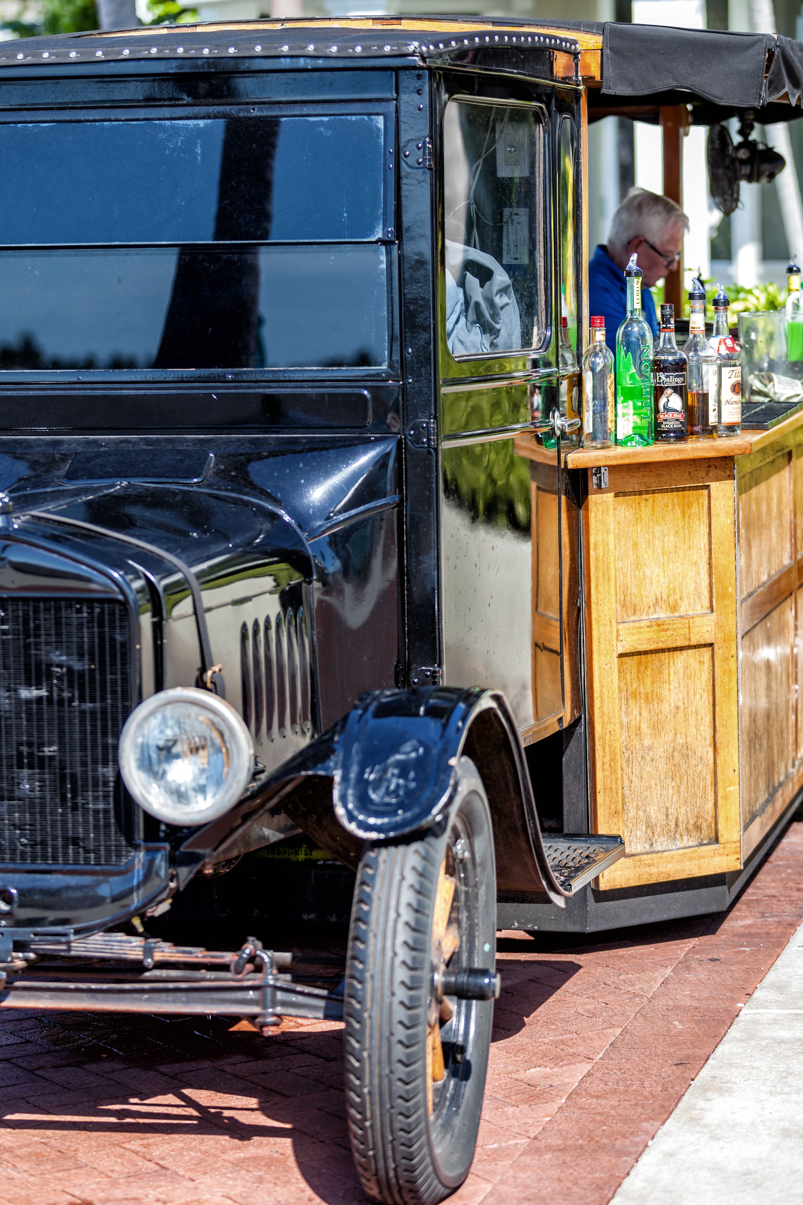 A vintage car with a wooden bar counter and bottles.