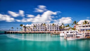 Un hôtel situé au bord de l’eau, doté de nombreux balcons, d’un quai et de bateaux.
