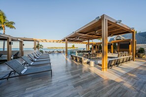 A deck with sun loungers, a bar area, and a view of the ocean. - Opal Key Resort & Marina, Key West (Key West)