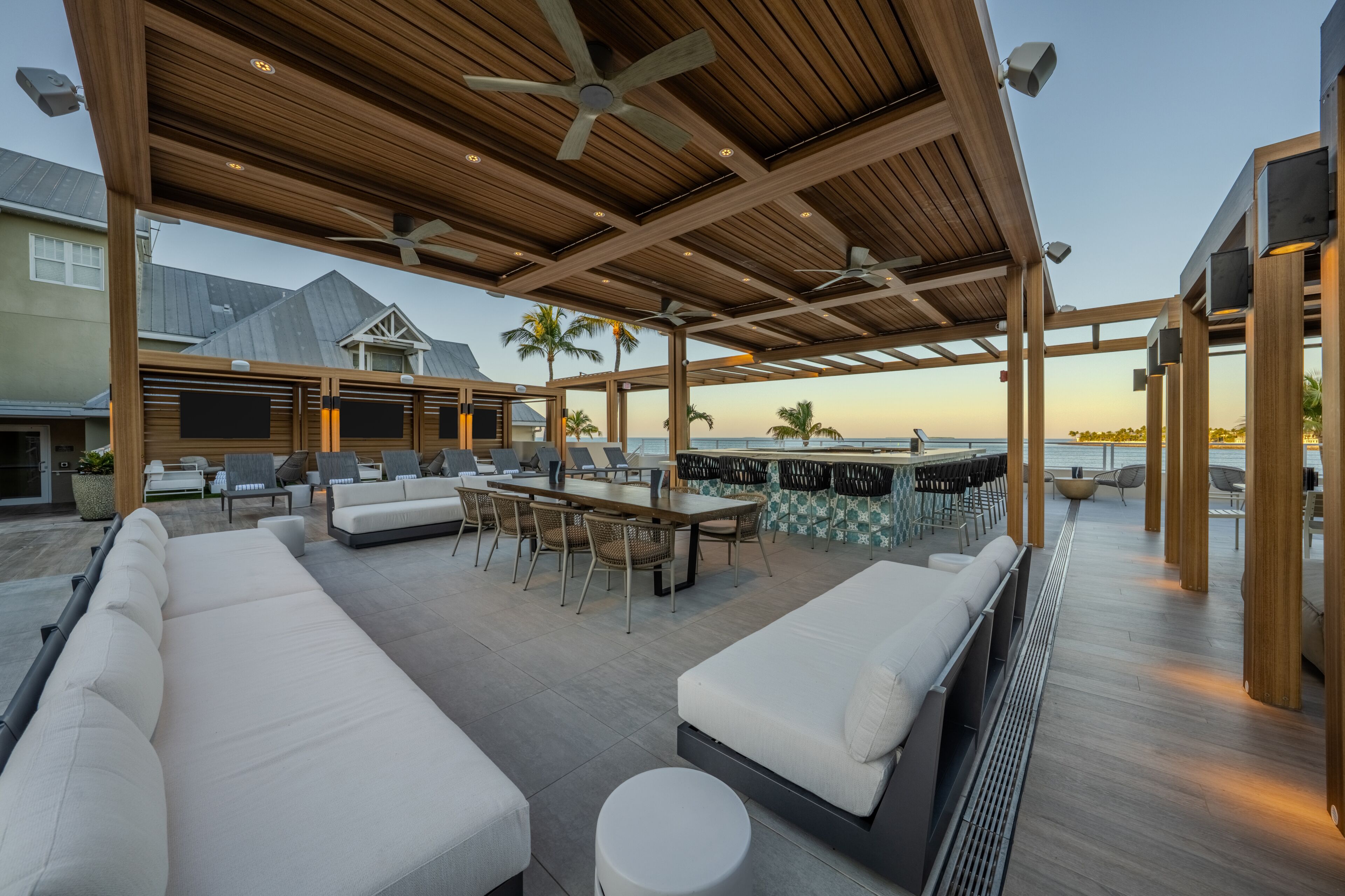 Une terrasse extérieure avec des poutres en bois, un espace repas et un bar avec des sièges.