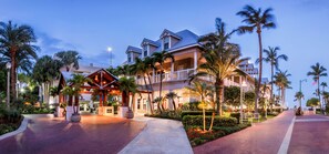 Un hotel con entrada techada, varios balcones y palmeras.