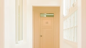 A hallway with a wooden floor, white walls, and a door labeled '11'. - Casa Baquedano (Santiago)