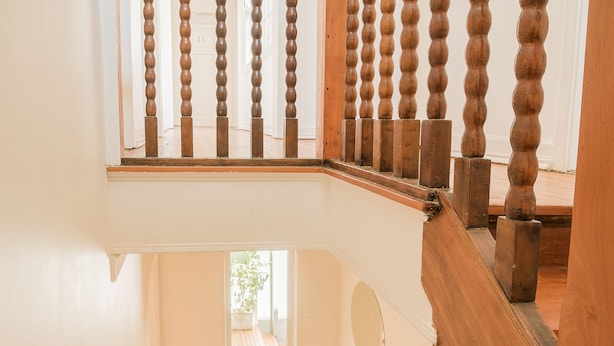 A wooden staircase with a balustrade leading to a landing. - Casa Baquedano (Santiago)