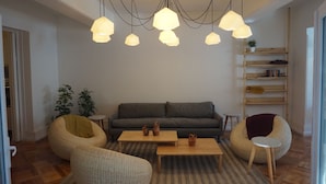 A modern living room with a grey sofa, two bean bag chairs, a coffee table, and a bookshelf. - Casa Baquedano (Santiago)