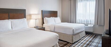 Habitación de hotel con dos camas, televisión, lámpara y ventana con cortinas.