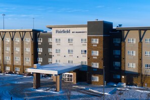 A Fairfield by Marriott hotel with multiple floors, a covered outdoor area, and a parking lot with snow.