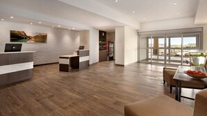 A modern hotel lobby with a reception desk, seating area, and a large window offering a view of the outdoors. - Fairfield Inn & Suites by Marriott Airdrie (Airdrie)
