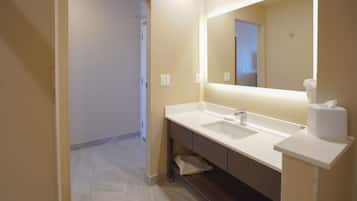 A modern bathroom with a white sink, mirror, and toilet paper dispenser.