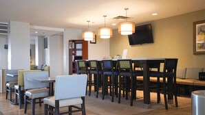 A modern hotel lobby with a reception desk, seating area, and a flat-screen TV mounted on the wall. - Fairfield Inn & Suites by Marriott Airdrie (Airdrie)