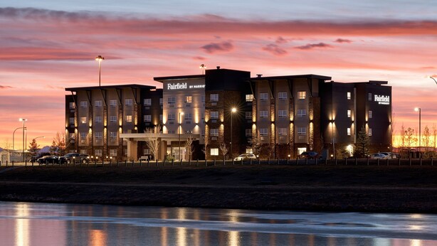 A multi-story hotel with a modern architectural design, featuring a prominent entrance and multiple windows. - Fairfield Inn & Suites by Marriott Airdrie (Airdrie)
