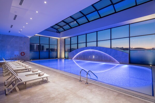 Una piscina cubierta, tumbonas