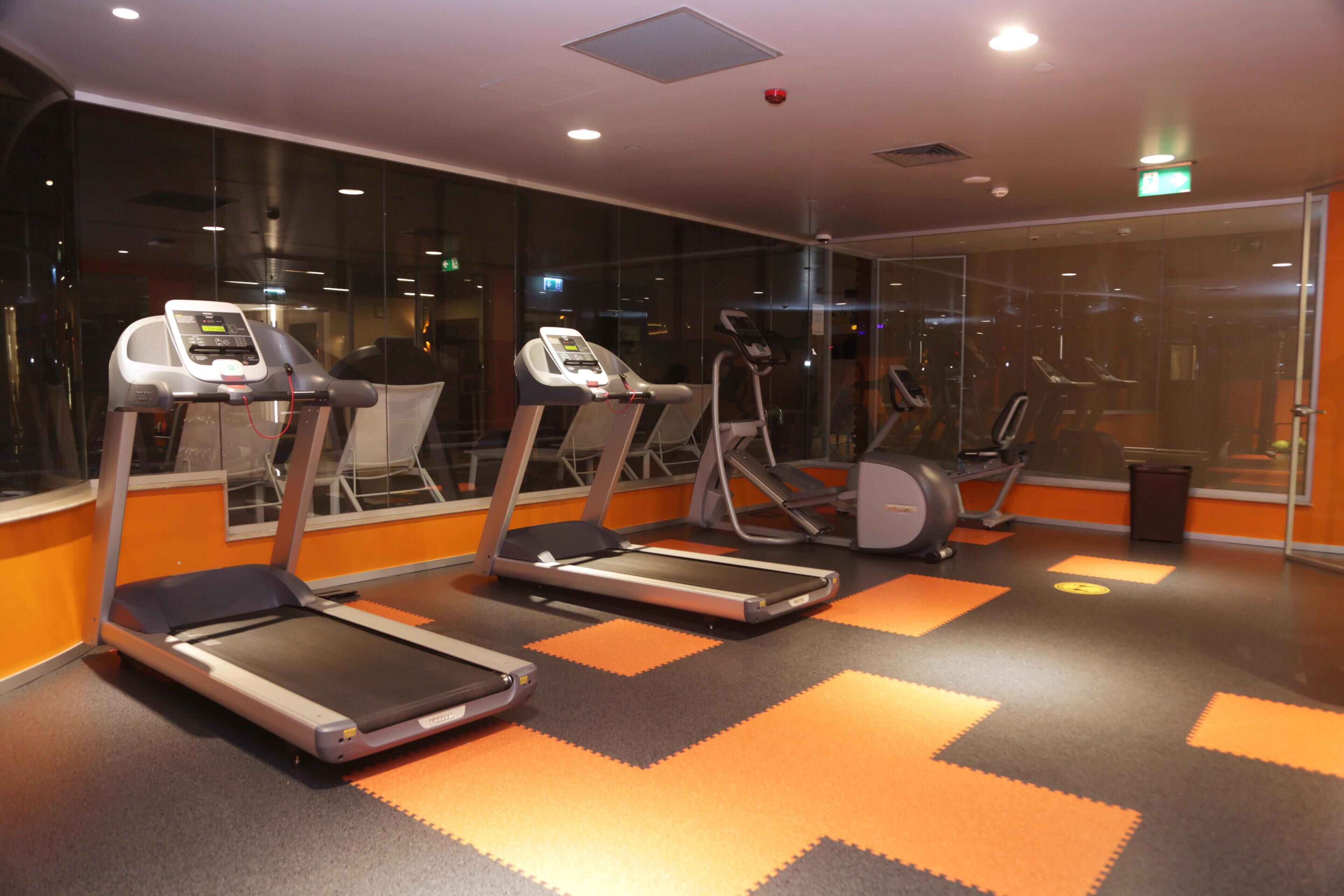 A gym with treadmills, exercise bikes, and a mirrored wall.
