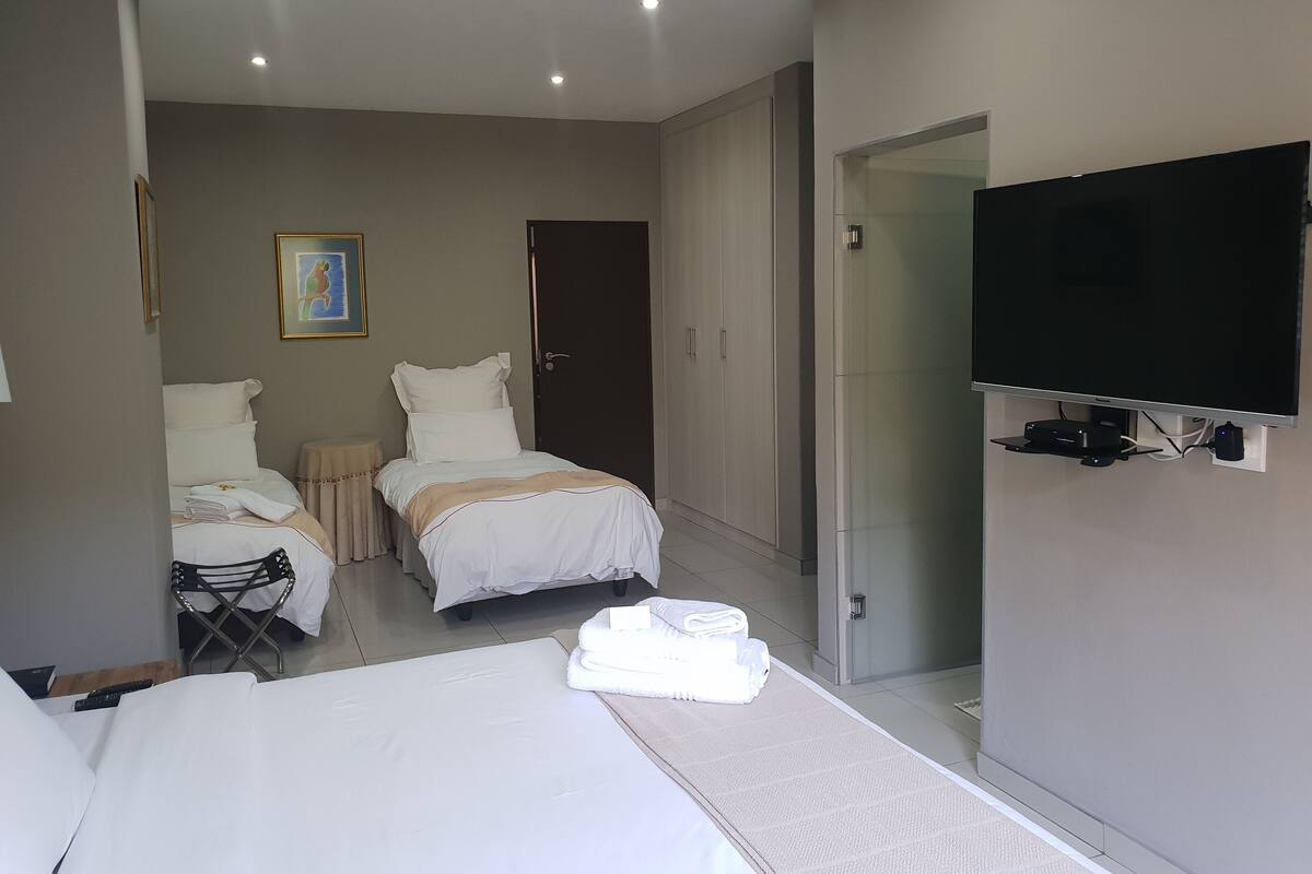 A hotel room with a bed, a chair, a TV, and a wardrobe.