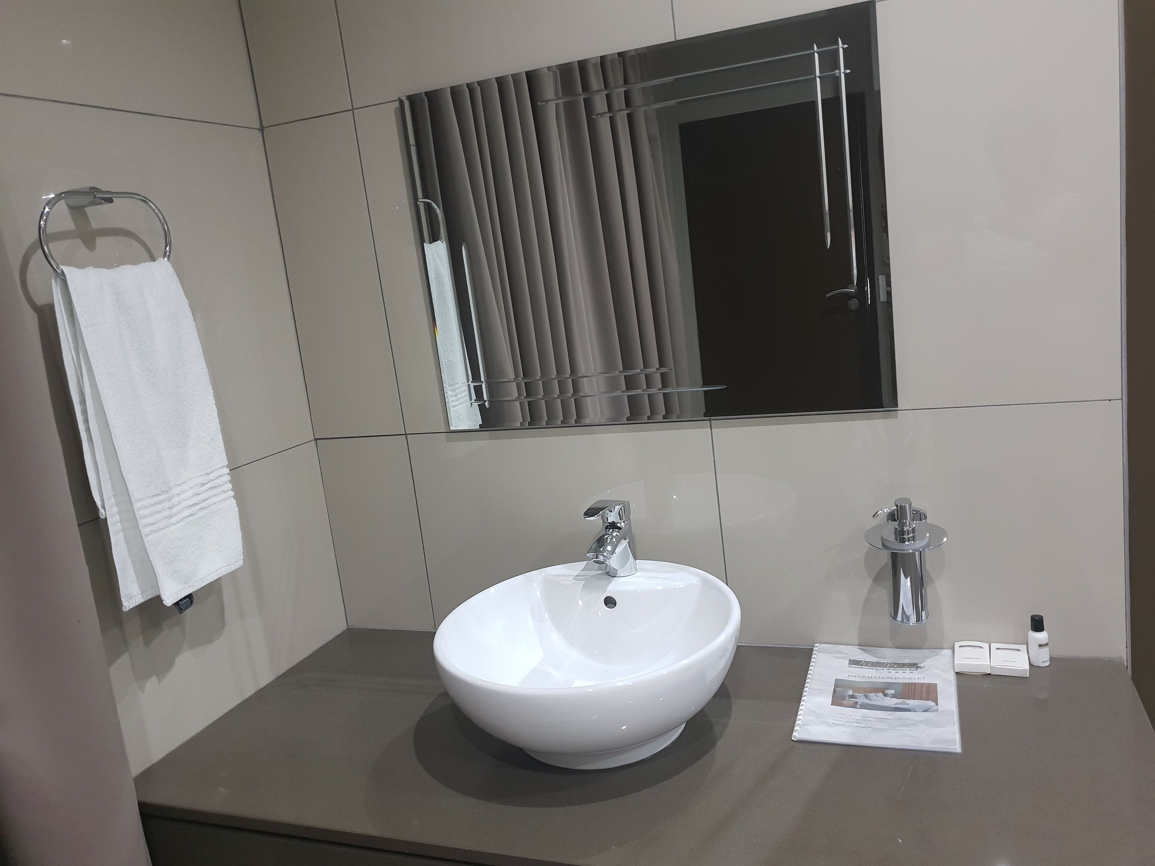 Un baño moderno con un lavabo blanco, un espejo y un perchero para toallas.