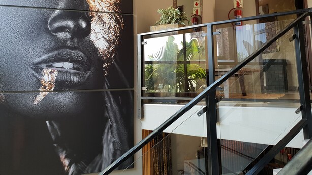Un escalier avec des rampes en verre et une grande fresque murale.