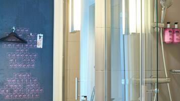 Une salle de bain moderne avec une douche à parois de verre, un lavabo blanc et un miroir qui reflète la pièce.