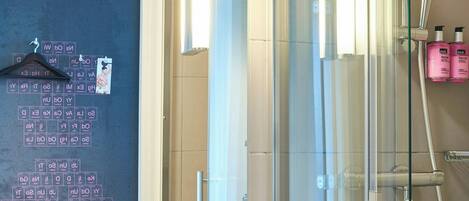 Un baño moderno con cabina de ducha de vidrio, un lavabo blanco y un espejo que refleja el cuarto.