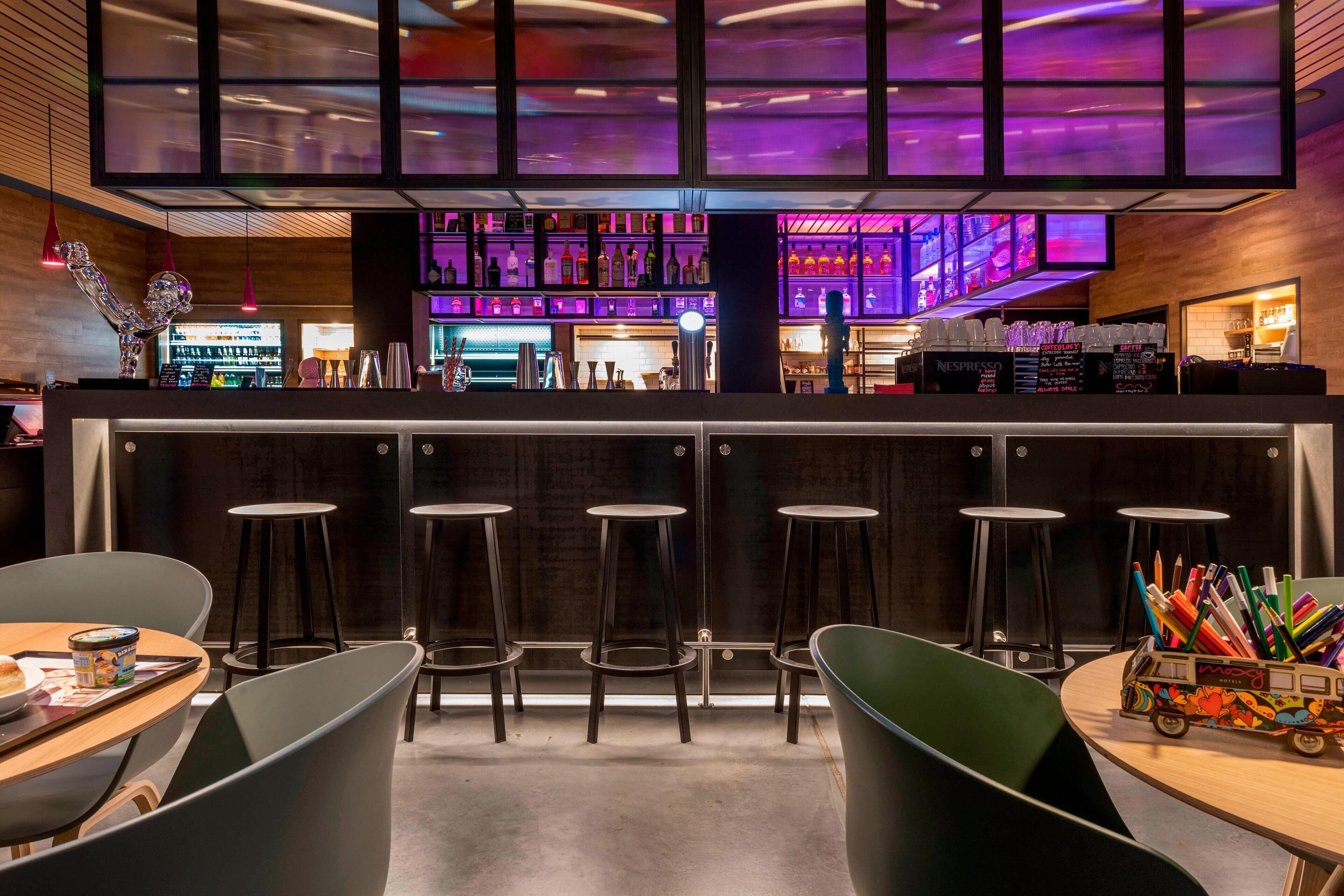 Een bar met krukken, een toonbank en een selectie drankjes.