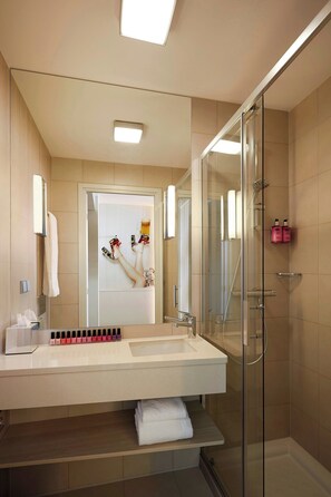 Un baño moderno con cabina de ducha de vidrio, un lavabo blanco y un espejo sobre él.