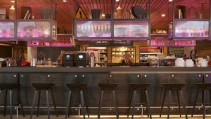 Un espace bar avec des tabourets, un comptoir et des étagères remplies de bouteilles.