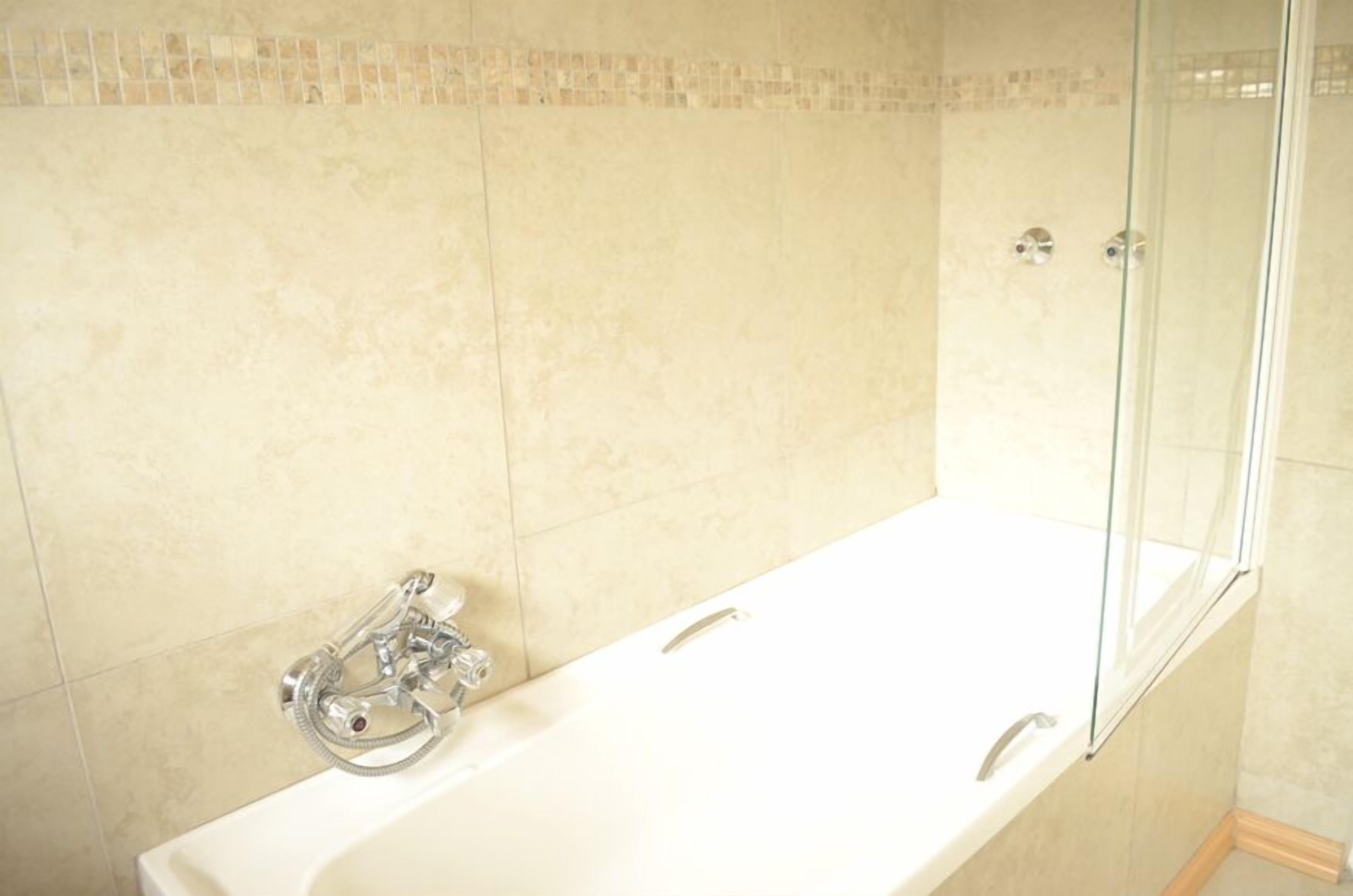 A modern bathroom with a freestanding bathtub, a glass shower enclosure, and tiled walls.