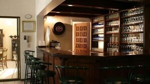 A bar area with a counter, bar stools, and shelves with glassware. - Ah Ha Guest House (Germiston)