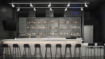 A bar area with a long counter, multiple shelves of bottles, and several black bar stools.