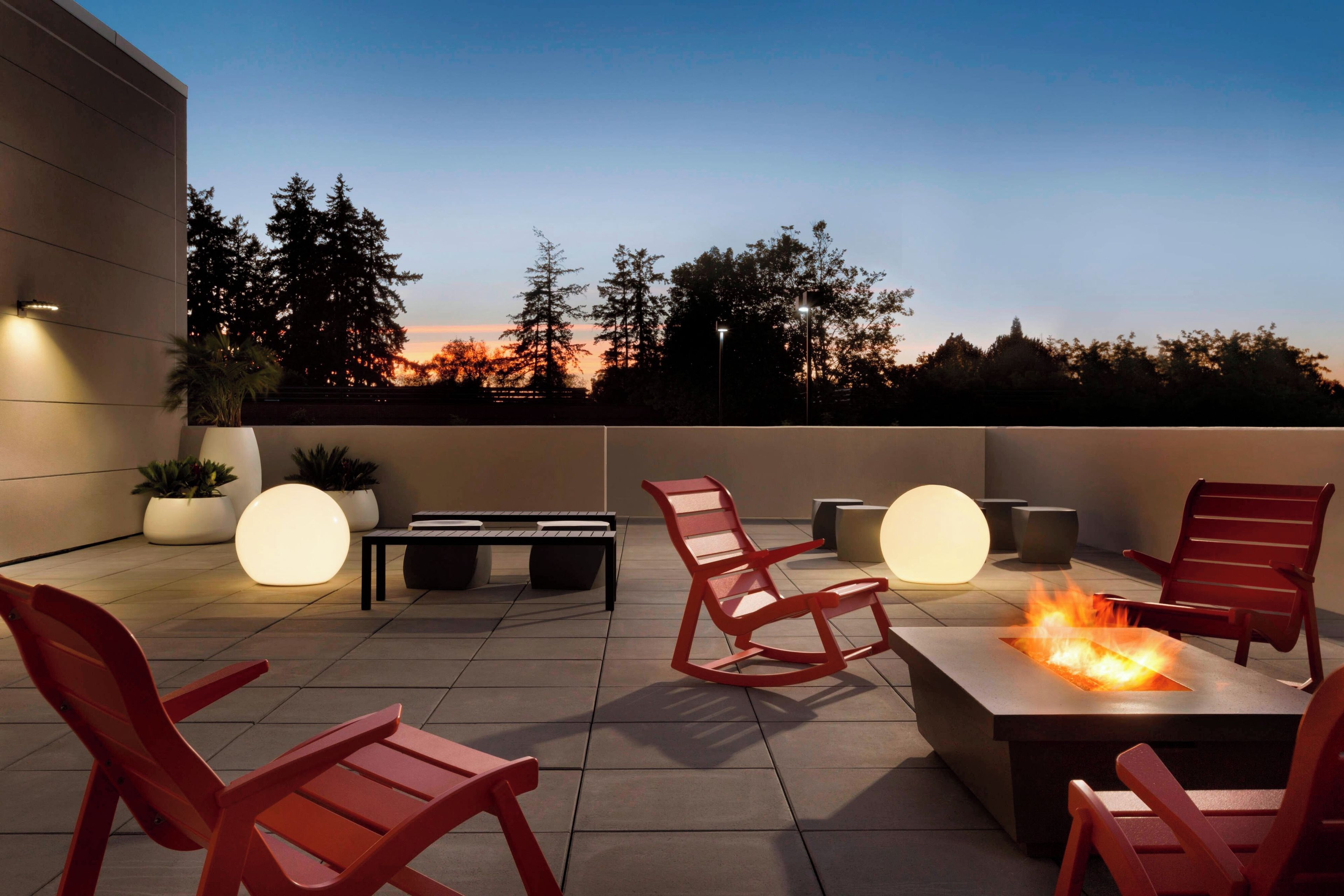 An outdoor patio with seating, a fire feature, and a view of the sunset.