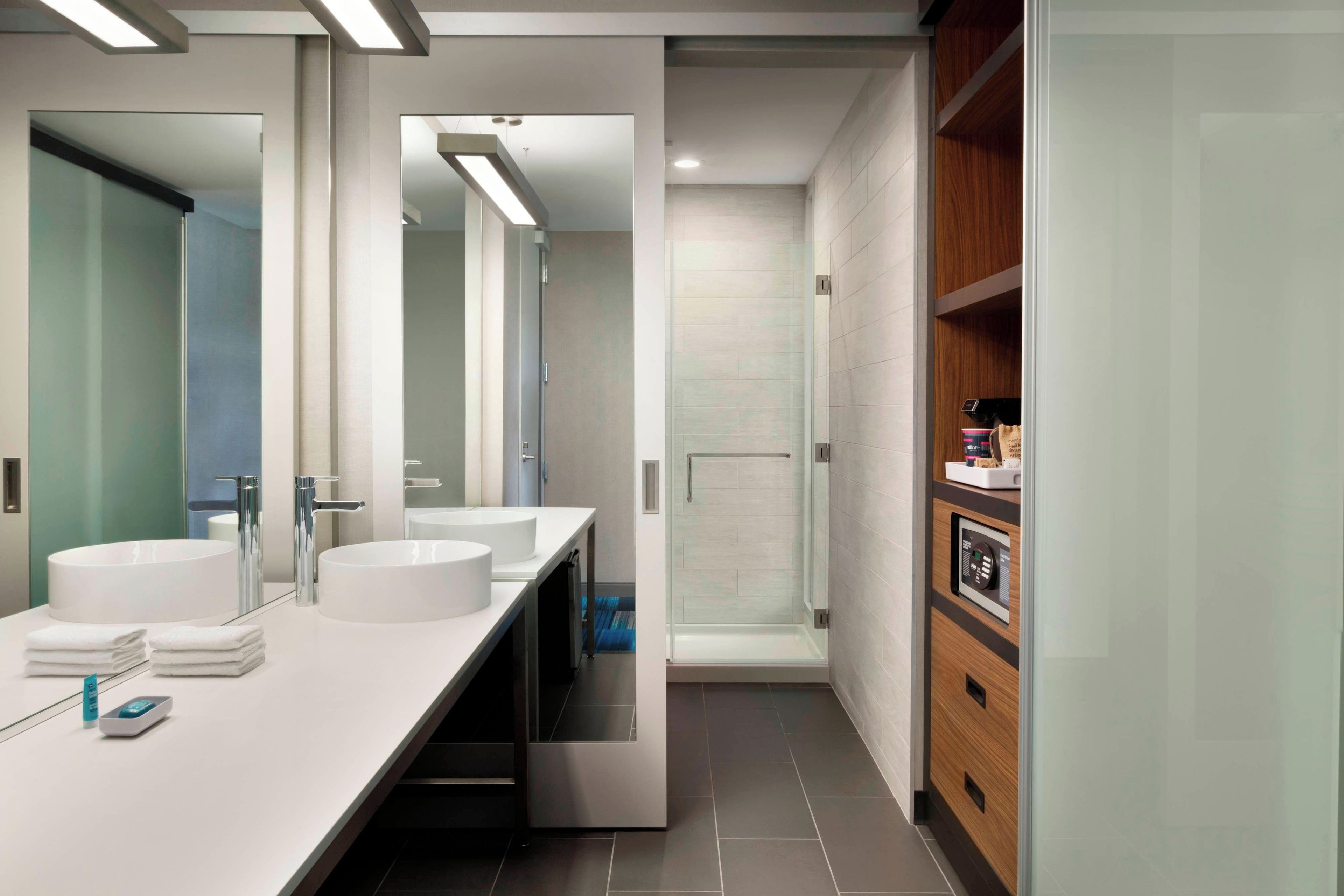 A modern bathroom with two sinks, a mirror, and a shower.