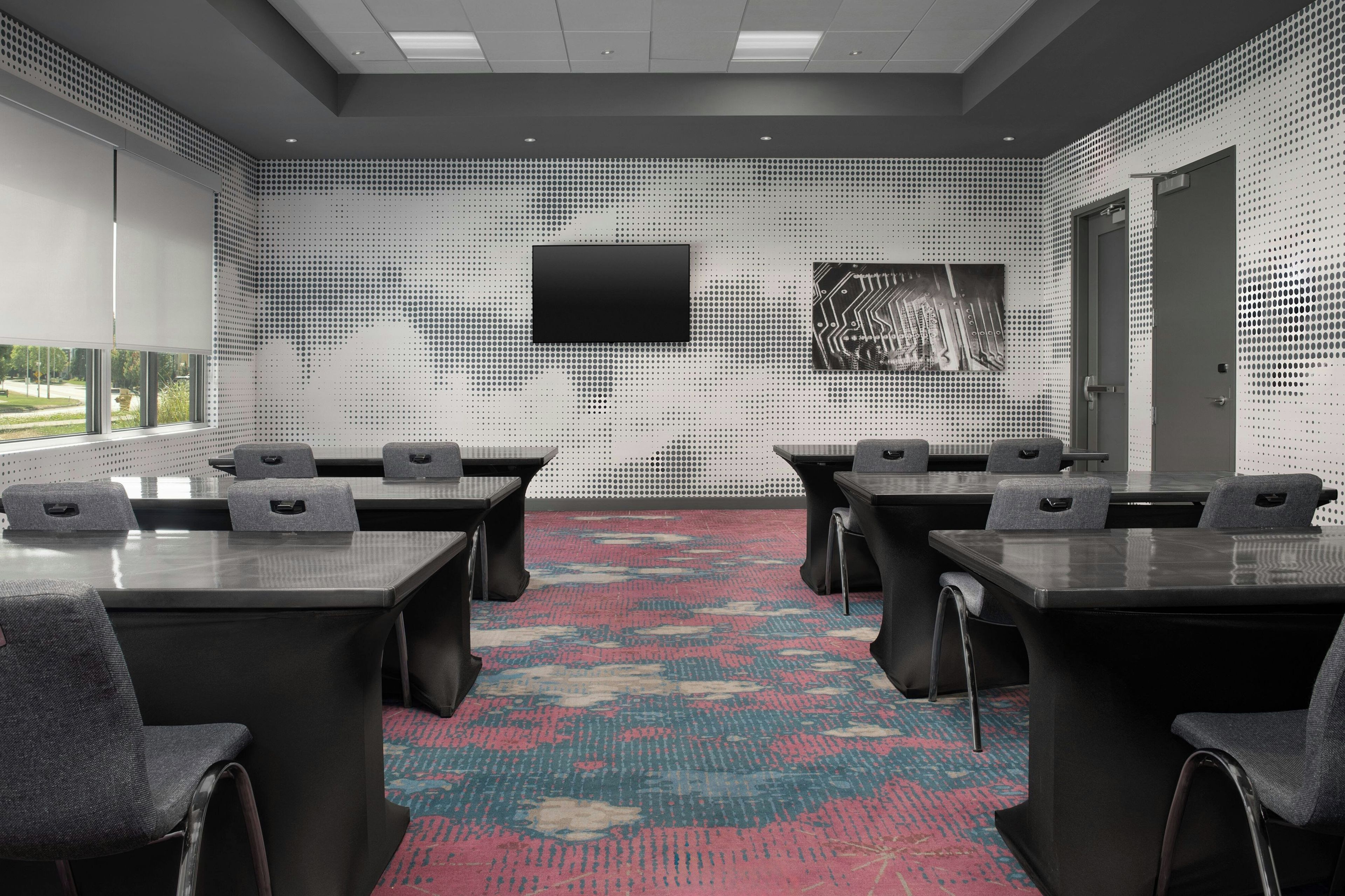 A conference room with a large screen, multiple tables, and chairs.