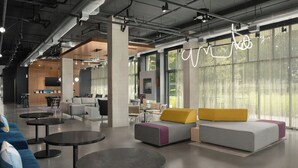 Un interno moderno con zone salotto, tavoli e ampie finestre.