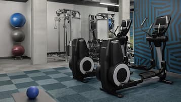 Ein Fitnessraum mit Trainingsgeräten, einer blauen Wand mit Muster und Übungsbällen.