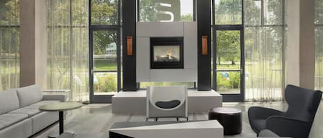 A modern living room with a fireplace, large windows, and contemporary furniture.
