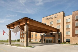 Un hotel con entrada cubierta, varios pisos y un letrero que dice 'COUNTRY INN & SUITES BY PADIBOSON'.