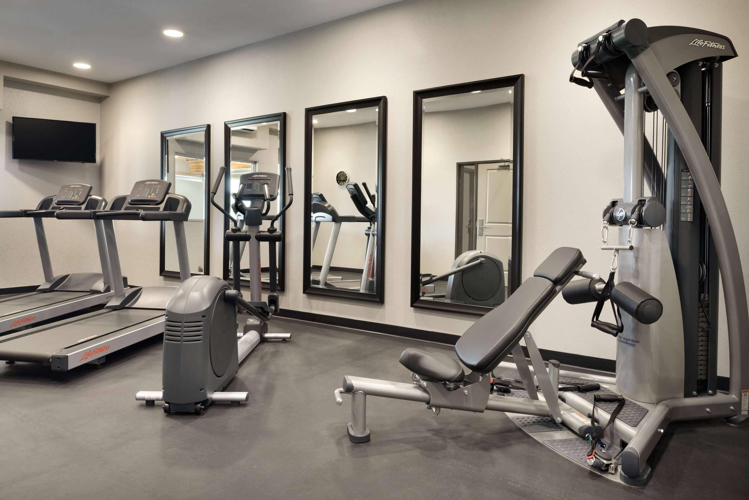 A gym with treadmills, elliptical machines, and weight equipment.